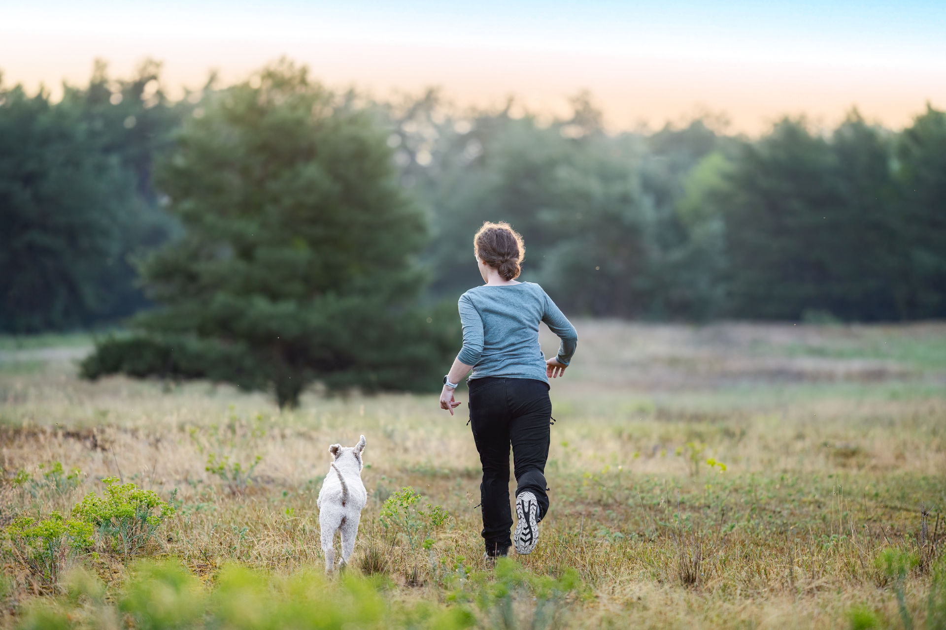 Marina Kern joggt im Morgenlicht mit ihrem Hund Maila über eine Wiese